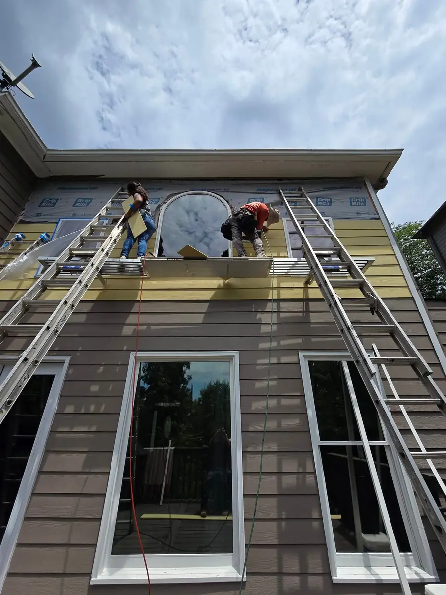 Workers repairing siding at an upper-story exterior wall